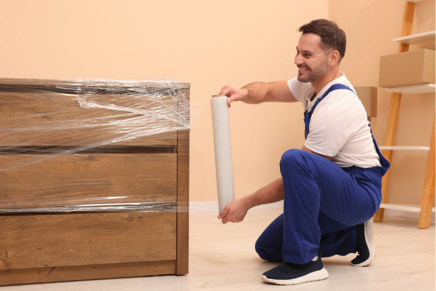 Male carpenter sawing a board with a circular saw in a carpentry workshop close-up